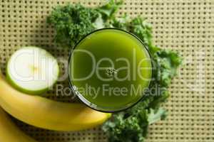 Fresh kale juice in glass with fruits on place mat