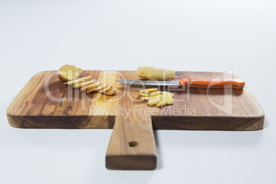 Close up of chopped ginger and knife on wooden cutting board