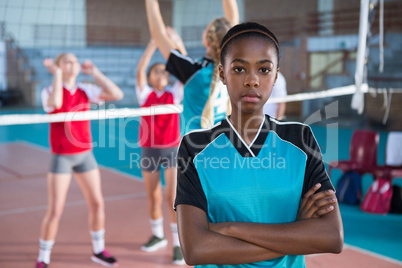 Female volleyball player standing with arms crossed in the court