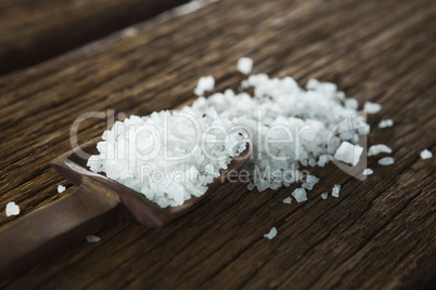 Salt in spoon on wooden table