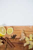 Overhead view of lemon and various spices on wooden serving board