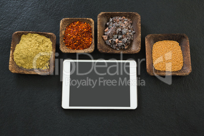 Various spices in bowl with digital tablet