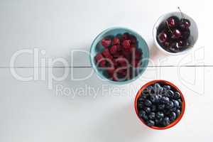 Overhead view of berries and cherries in bowls