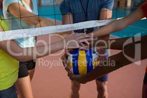 Coach and female players holding volleyball