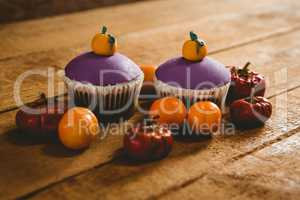 Cup cakes with small pumpkins on wooden table