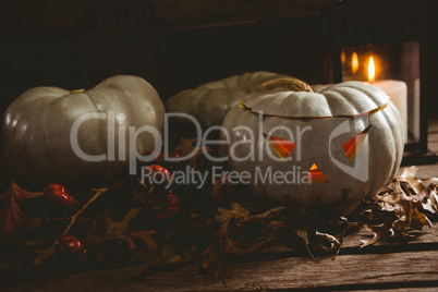 White jack o lanterns with autumn leaves on table