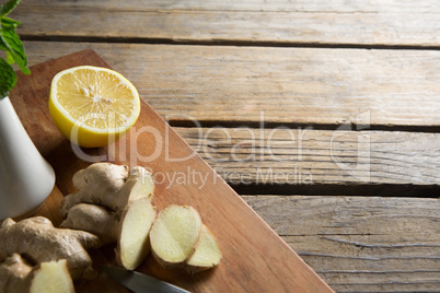 Close-up of ginger with lemon on cutting board over table
