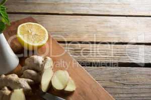 Close-up of ginger with lemon on cutting board over table