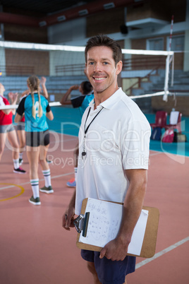 Smiling coach standing in the volleyball court