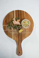 Overhead view of ginger and rosemary on wooden serving board