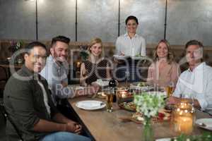 Portrait of happy waitress and customers at dining table