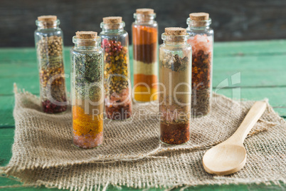 Various spices in bottles on wooden table