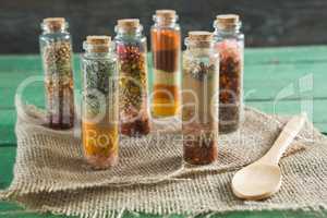 Various spices in bottles on wooden table