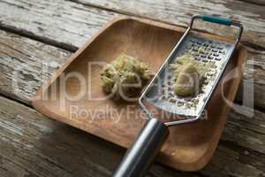 High angle view of grater with ginger on plate over table