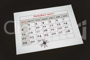 Artificial spider on calender over black background