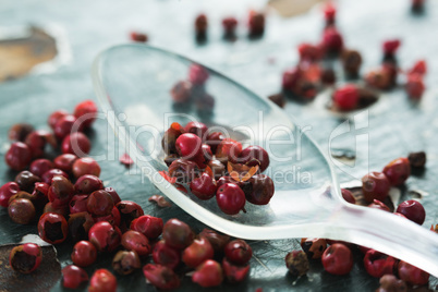 Pink peppercorn and spoon on wooden table