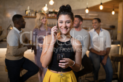Beautiful woman talking on mobile phone while having wine