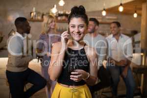 Beautiful woman talking on mobile phone while having wine