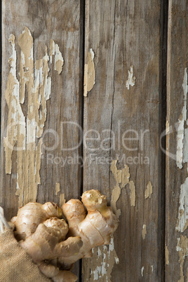 Overhead view of fresh gingers in burlap sack on weathered table