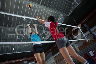 Female players playing volleyball in the court