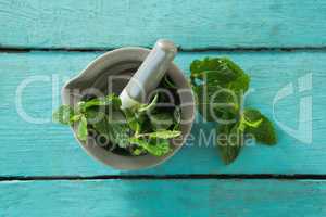 Mint leaves with mortar and pestle on wooden table