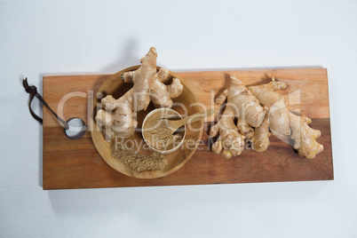 High angle view of fresh ginger and powder on wooden serving board