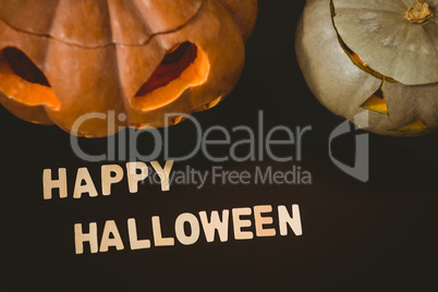Happy Halloween text by jack o lanterns over black background