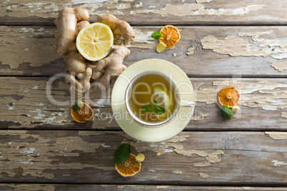 Overhead view of lemon and mint leaves in ginger tea on weathered table