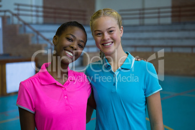 Smiling female players standing together in volleyball court