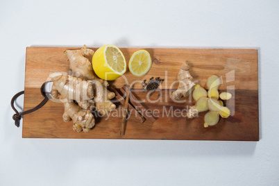 Directly above view of lemon and various spices on wooden serving board