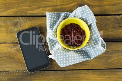 Pink peppercorn in bowl and mobile phone