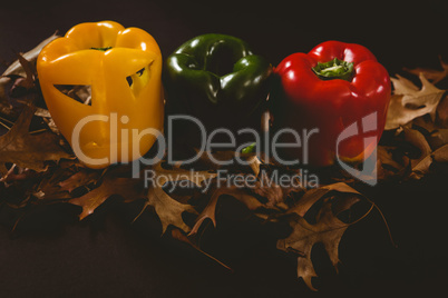 Carved bell peppers with autumn leaves over black background