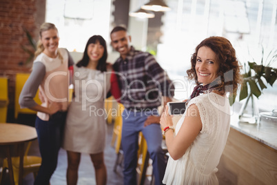 Portrait of smiling woman photographing young friends from smartphone