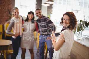 Portrait of smiling woman photographing young friends from smartphone