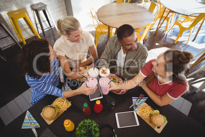 High angle view of smiling young friends raising toast while sitting at coffee shop