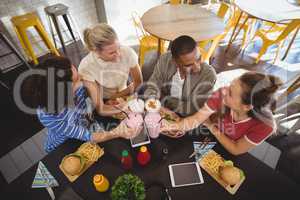 High angle view of smiling young friends raising toast while sitting at coffee shop