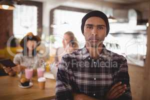 Portrait of confident man with arms crossed standing against female friends