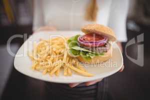 Midsection of waitress holding fresh burger and fries in plate