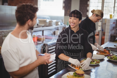Cheerful waiter and female chef working in kitchen