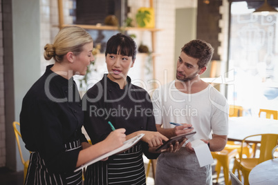 Young wait staff discussing over tablet computer at coffee shop