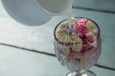 Milk being pour into glass of honeycomb cereal