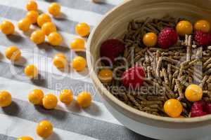 Bowl of cereal bran stick with golden berries and raspberries