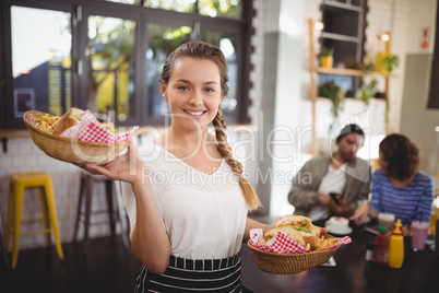 Portrait of smiling young waitress carrying food in wicker baskets