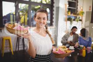 Portrait of smiling young waitress carrying food in wicker baskets