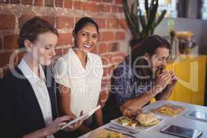 Portrait of smiling young woman sitting amidst friends at table with food