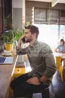 Smiling young man talking on cellphone while sitting at coffee shop