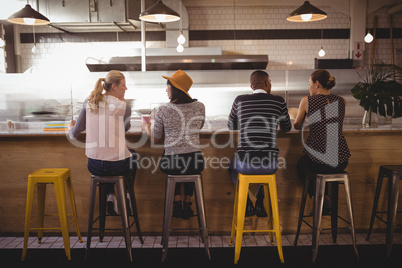 Rear view of friends sitting on stool at counter