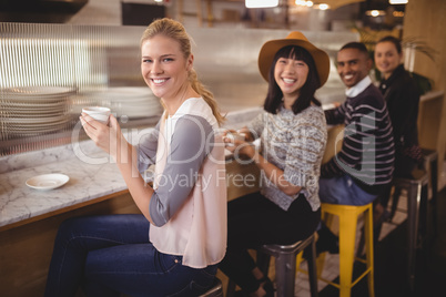 Portrait of smiling young friends sitting with coffee