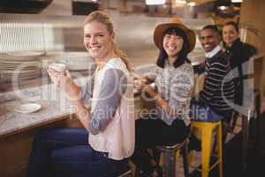 Portrait of smiling young friends sitting with coffee
