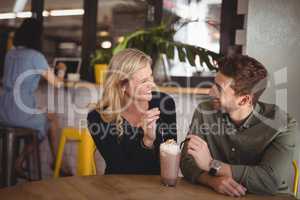 Smiling couple with fresh dessert while sitting at coffee shop